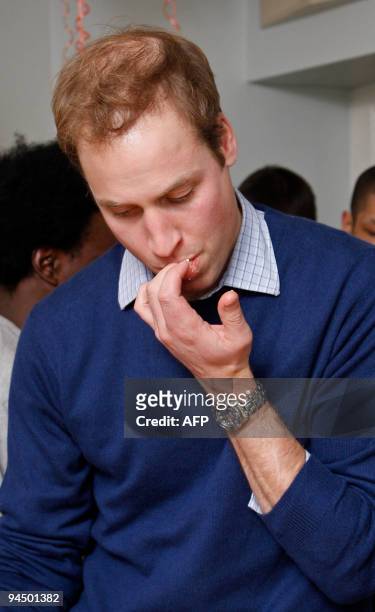 Britain's Prince William licks icing off of his fingers after cutting a birthday cake during a visit to the charity Centrepoint, on their 40th...