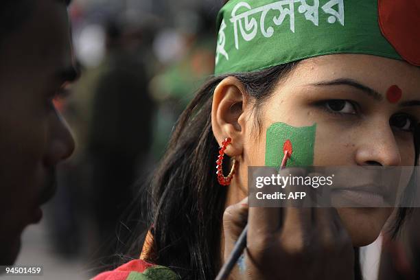 Bangladeshi woman has the national flag painted on her cheek during a rally held to mark the country's 38th Victory Day in Dhaka on December 16,...