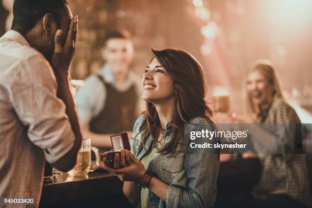 happy woman proposing to her boyfriend in a bar. - marriage proposal woman stock pictures, royalty-free photos & images