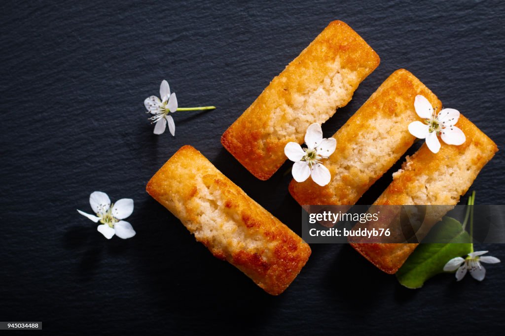 Food concept mini French almond cake financier on black slate stone with copy space