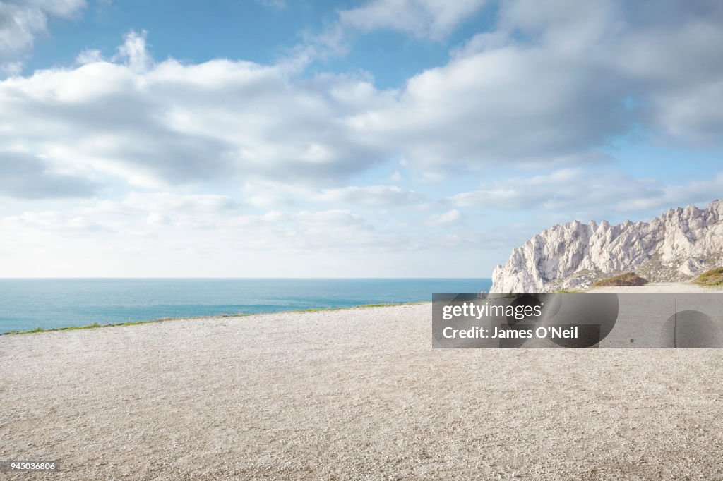 Flat gravel plateau next to ocean with background rocks