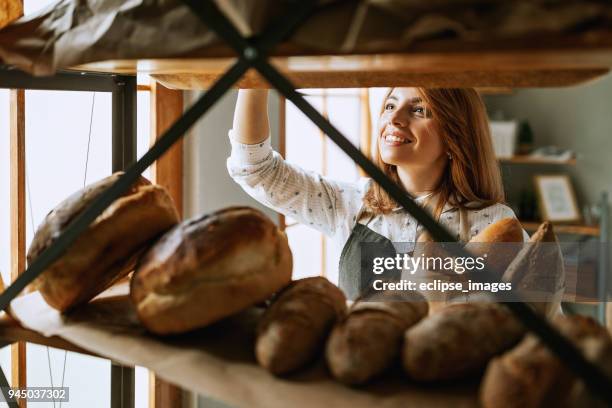 ung kvinna merchandise bröd i butik - artisan food bildbanksfoton och bilder