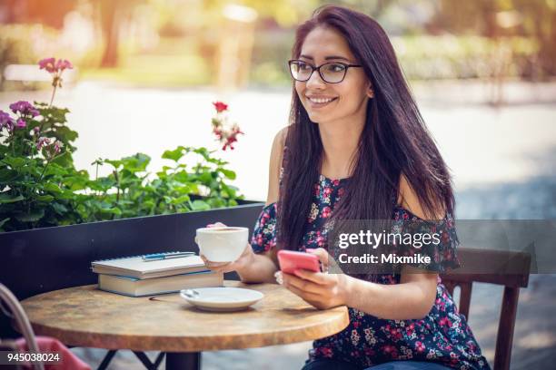 brunette vrouw texting op haar telefoon in het café - 2017 common good forum stockfoto's en -beelden