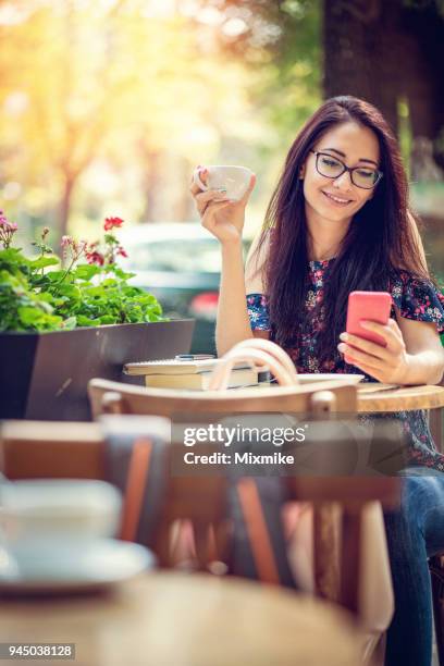 young woman browsing on her phone at the café - 2017 common good forum stock pictures, royalty-free photos & images