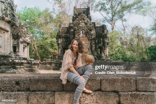frau, sitzen und trinken kokosnuss im tempel von angkor in kambodscha - angkor wat stock-fotos und bilder