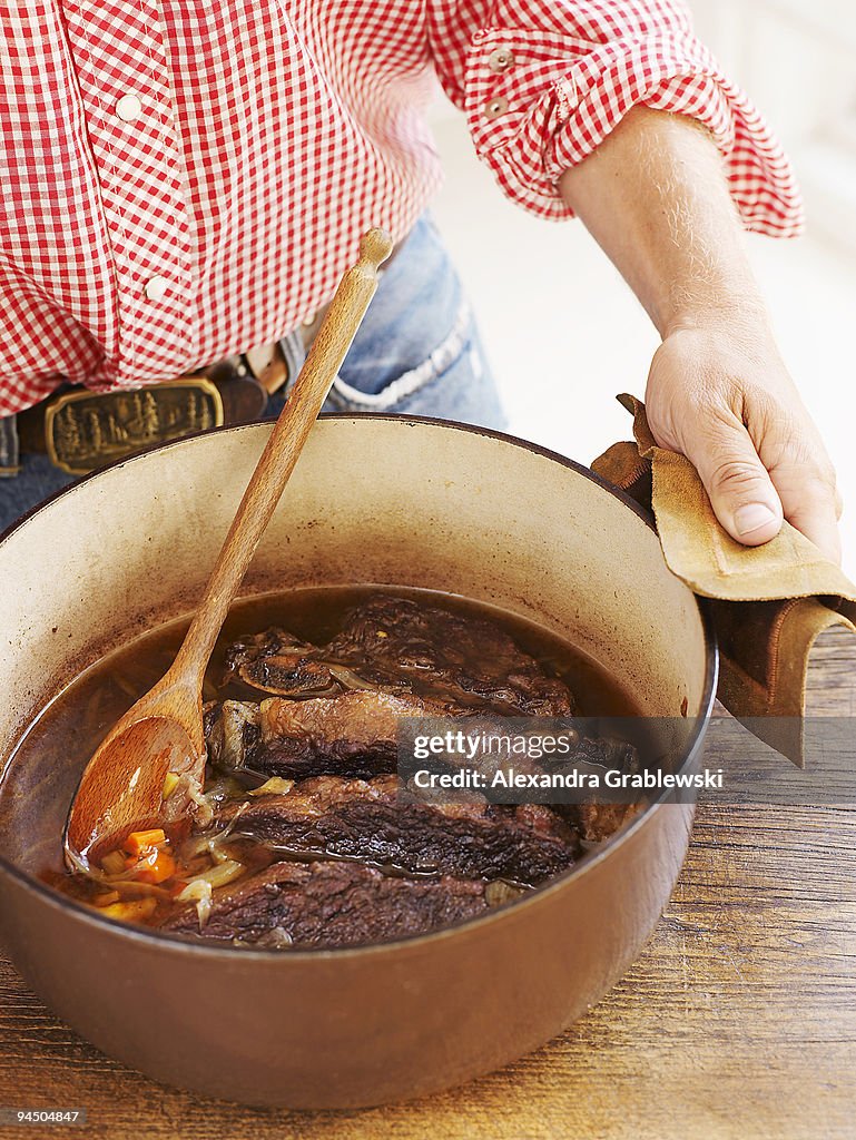 Man Holding Pot of Maple Syrup Braised Short Ribs