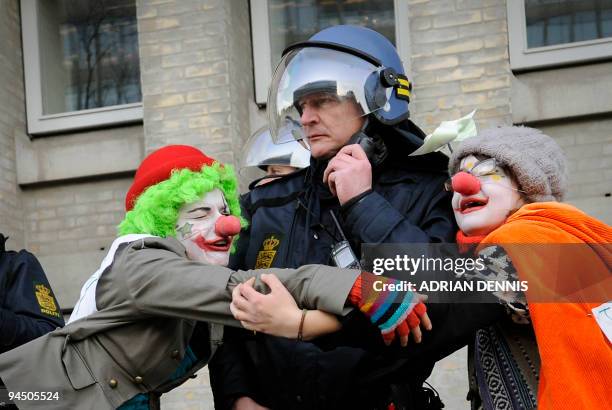 Climate change demonstrators dressed as clowns hug a police officer outside the Danish Foreign Ministry while demonstrators pass during the climate...