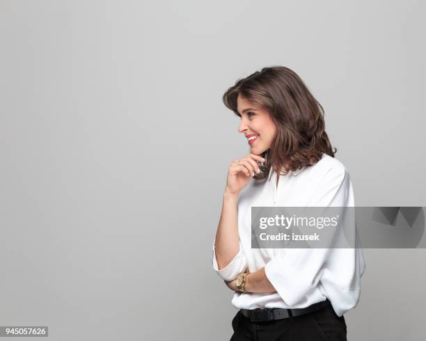 side view of beautiful young businesswoman against grey background - women standing against grey background stock pictures, royalty-free photos & images