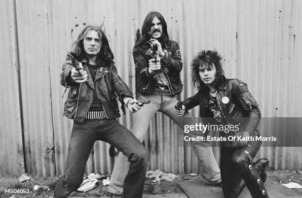 British heavy rock band Motorhead pose with pistols, London, 1978. Left to right: guitarist 'Fast' Eddie Clarke, bassist and singer Lemmy and drummer...