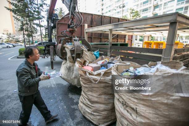 The manager of an apartment complex picks up plastic bottles as a crane claw picks up bags of plastic waste in Yongin, South Korea, on Wednesday,...