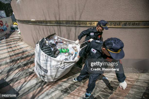 Security guards at an apartment complex move a bag of plastic waste to be picked up by waste collectors in Yongin, South Korea, on Wednesday, April...