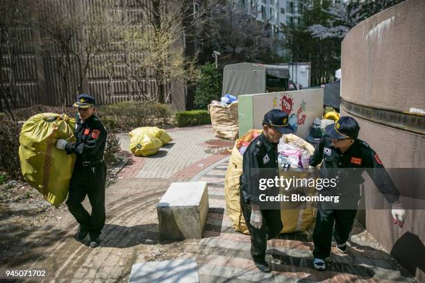 Security guards at an apartment complex move bags of plastic waste to be picked up by waste collectors in Yongin, South Korea, on Wednesday, April...