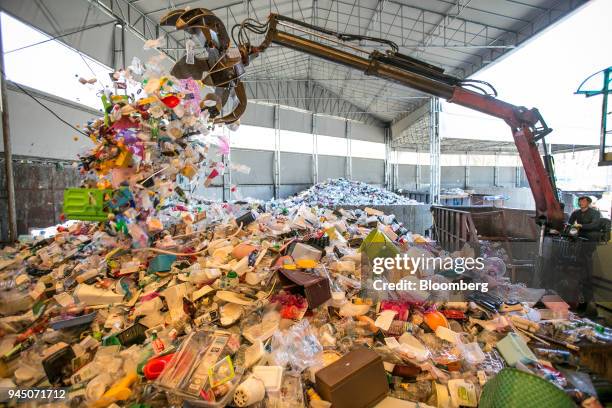 Worker operates a crane claw as it unloads plastic waste onto a stockpile at a recycling center in Yongin, South Korea, on Wednesday, April 11, 2018....