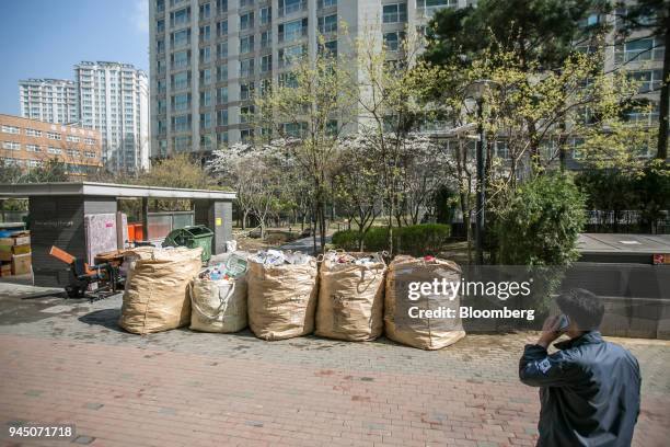 Bags of uncollected plastic waste sit outside an apartment complex as a building manager looks on in Yongin, South Korea, on Wednesday, April 11,...
