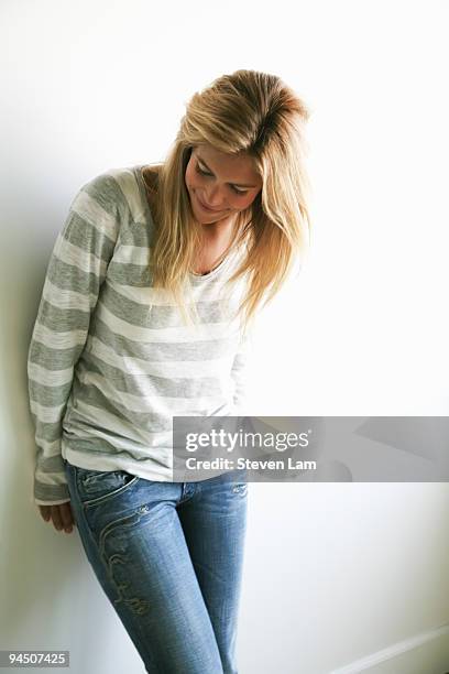 woman smiling leaning on wall looking down on floo - woman smiling facing down stock pictures, royalty-free photos & images