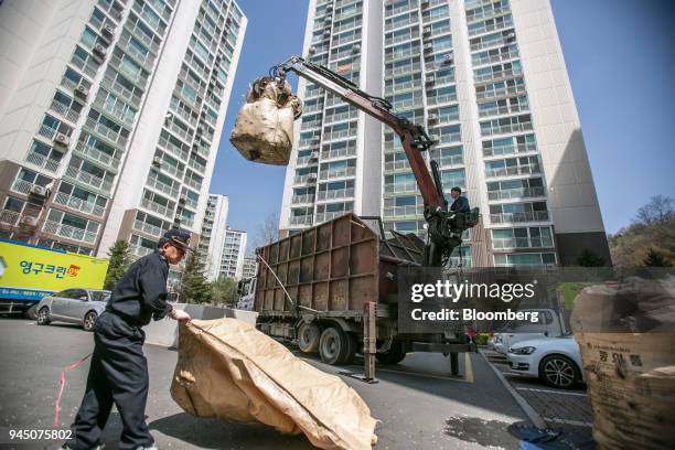 Waste collector operates a crane to pick up a bag of plastic waste outside an apartment complex in Yongin, South Korea, on Wednesday, April 11, 2018....