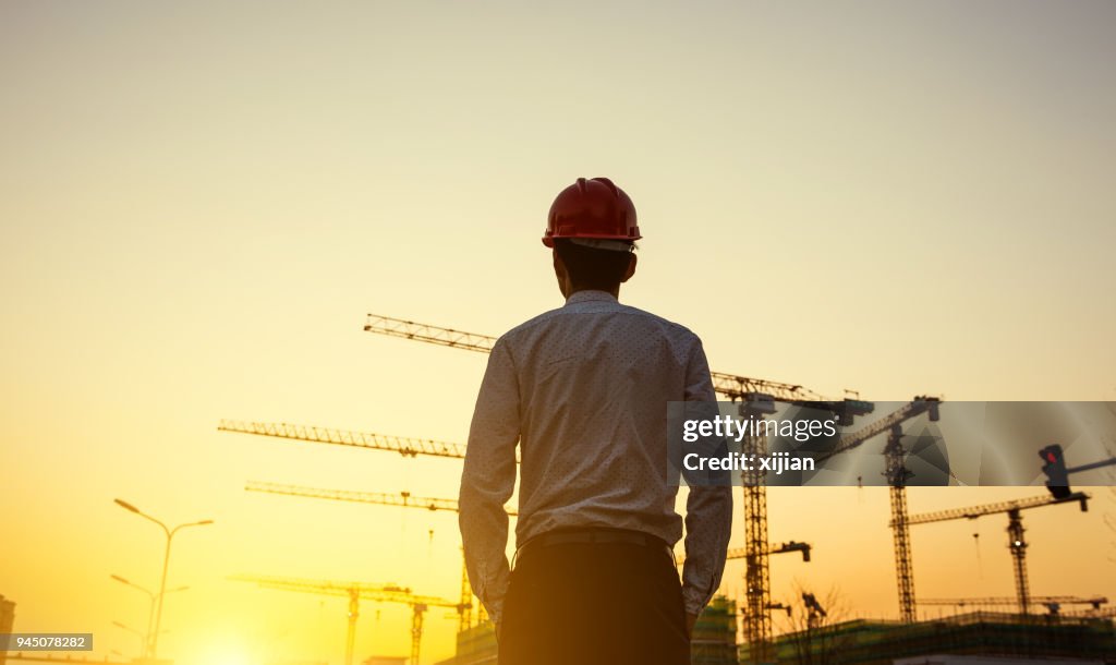 Engineer with crane background at sunset