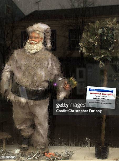 Santa Claus statue stands behind a condensation covered shop window in Cockermouth High Street on December 16, 2009 in Cockermouth, England. An army...