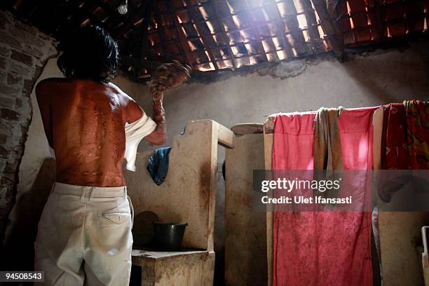 Indonesian man Dede Koswara bath with the way in flush with a damp cloth in his home village on December 16, 2009 in Bandung, Java, Indonesia. Due to...