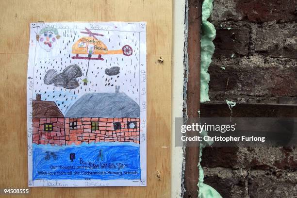 Drawing of a helicopter rescue by a pupil of Cockermouth Primary Schools adorns a flood damaged shop on the High Street on December 16, 2009 in...