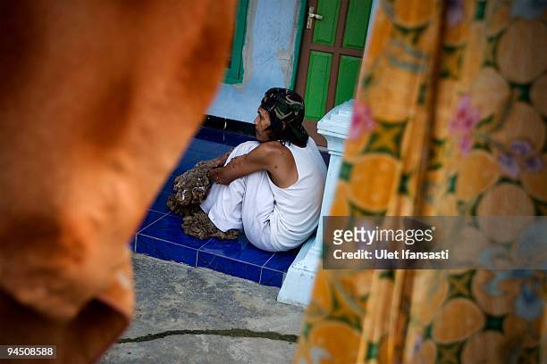 Indonesian man Dede Koswara sitting in front house in his home village on December 16, 2009 in Bandung, Java, Indonesia. Due to a rare genetic...