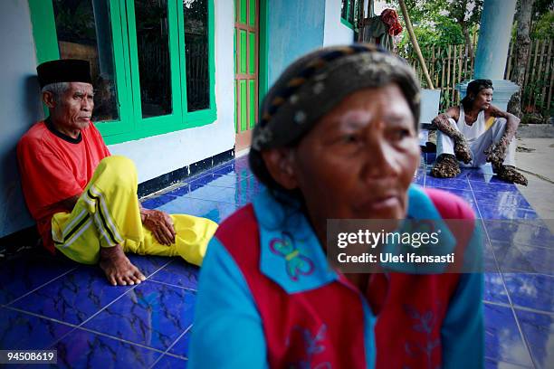 Indonesian man Dede Koswara sitting in front house with his parents in his home village on December 16, 2009 in Bandung, Java, Indonesia. Due to a...