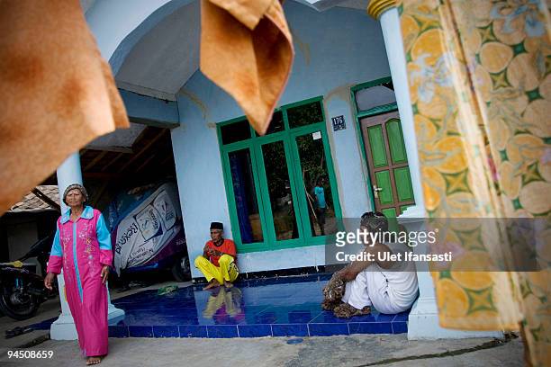 Indonesian man Dede Koswara sitting in front house with his parents in his home village on December 16, 2009 in Bandung, Java, Indonesia. Due to a...