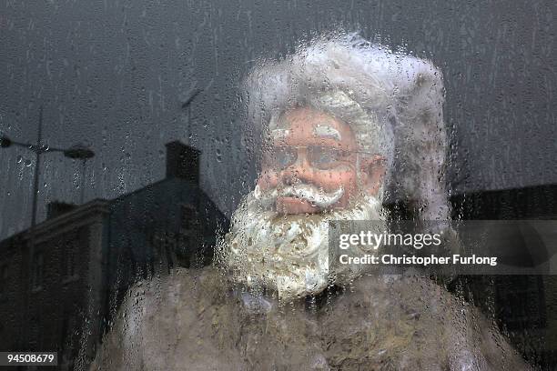 Santa Claus statue stands behind a condensation covered shop window in Cockermouth High Street on December 16, 2009 in Cockermouth, England. An army...