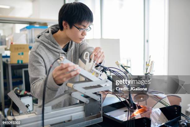 engineering student arbetar på en medicinsk maskin - robotarm tillverkningsutrustning bildbanksfoton och bilder