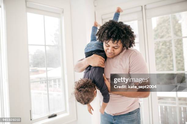 a man holding a girl upside down - holding upside down stock pictures, royalty-free photos & images