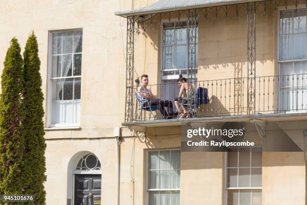 jovem casal sentou-se numa varanda pequena do ferro em uma casa georgiana, desfrutando de um calmo ensolarado manhã de domingo em cheltenham, gloucestershire - couch potato expressão em inglês - fotografias e filmes do acervo