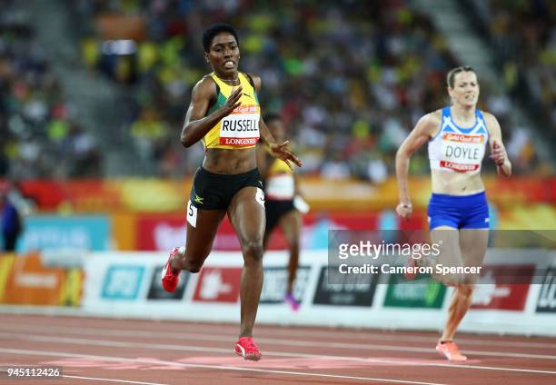 Janieve Russell of Jamaica crosses the line to win gold ahead of Eilidh Doyle of Scotland in the Women's 400 metres hurdles final during athletics on...