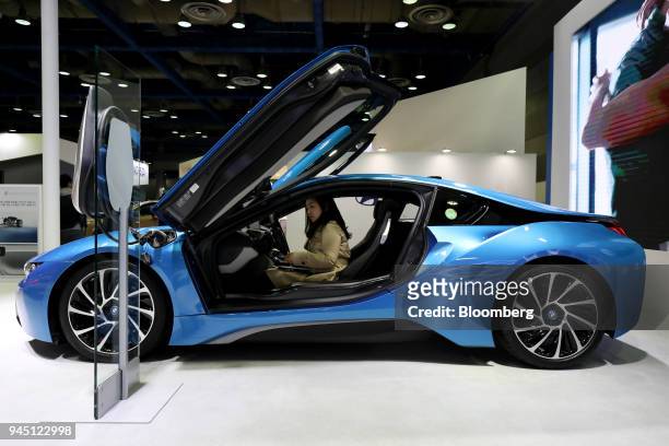 An attendee sits inside a BMW AG i8 plug-in coupe vehicle at the EV Trend Korea exhibition in Seoul, South Korea, on Thursday, April 12, 2018. The...