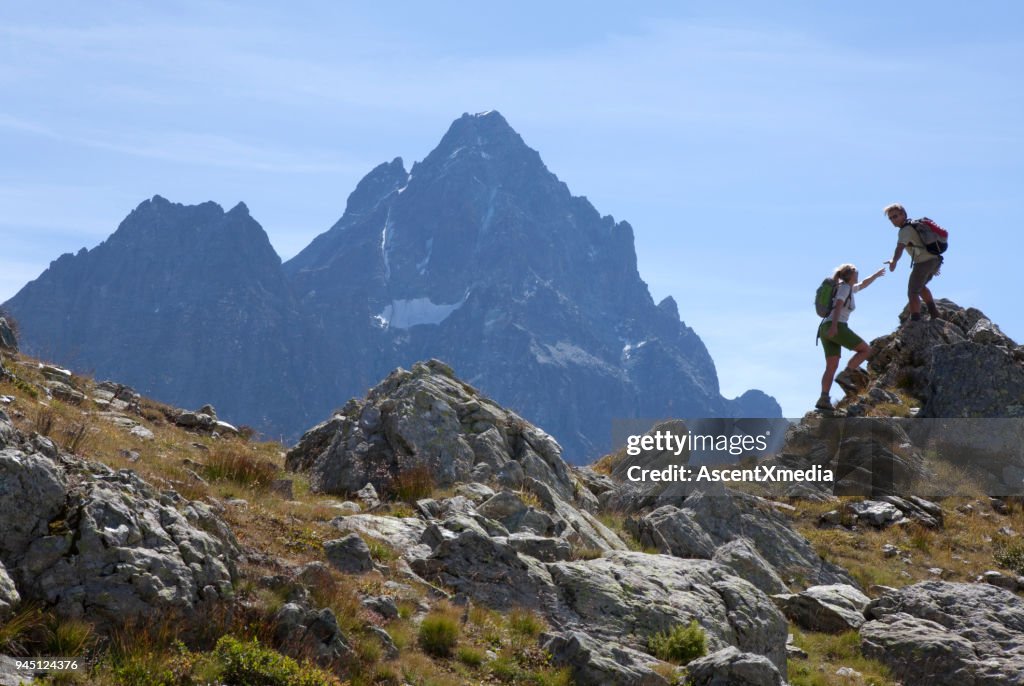 Escursionista offre mano a compagno, su cresta di montagna, Piemonte, Italia