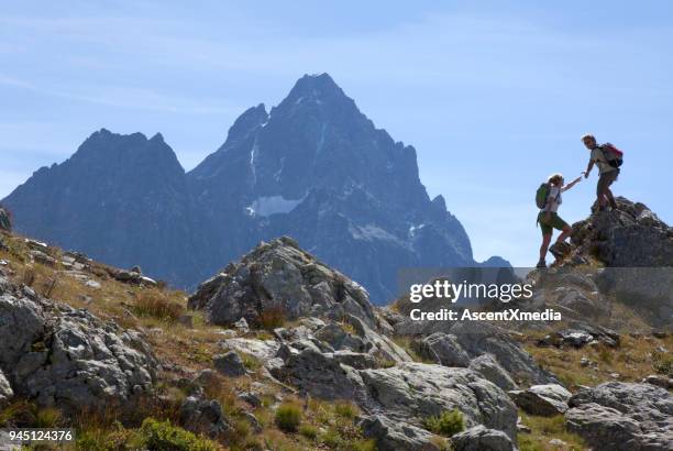 hiker offers hand to companion, on mountain ridge, piedmont, italy - european alps stock pictures, royalty-free photos & images