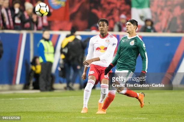Tyler Adams of New York Red Bulls challenged by Alan Pulido of C.D. Guadalajara during the New York Red Bulls Vs C.D. Guadalajara CONCACAF Champions...