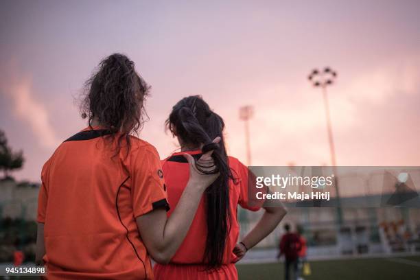 Two girls playing for the U-15 team of the Jordanian Football Club Shabaab Al Ordon watch their training session on April 3, 2018 in South Amman,...