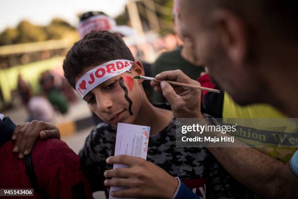 Fan of the Jordanian Womens Football Team is getting the Jordanian flag painted on his face while standing in line to enter Amman Stadium the opening...