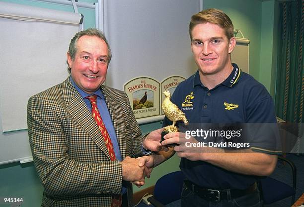 Tim Horan of Australia receives his award from Gareth Edwards during the Rugby Union World Cup 1999 Famous Grouse player of the tournament awards...