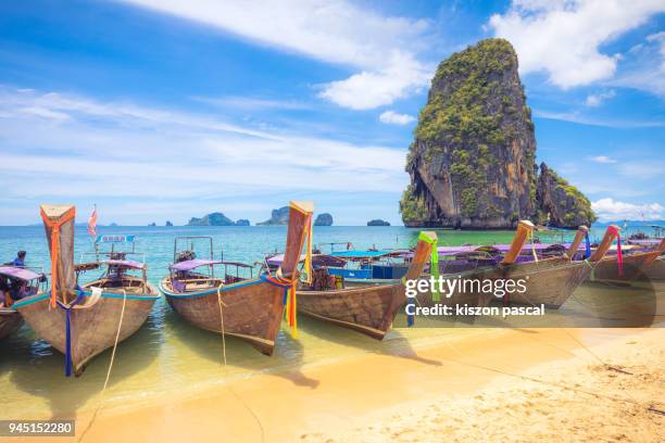 long tail boat on railay beach in krabi during a sunny day , thailand , asia - long tail boat stock-fotos und bilder