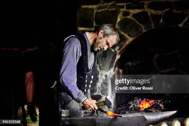 blacksmith at work in smithy - fabbro ferraio foto e immagini stock