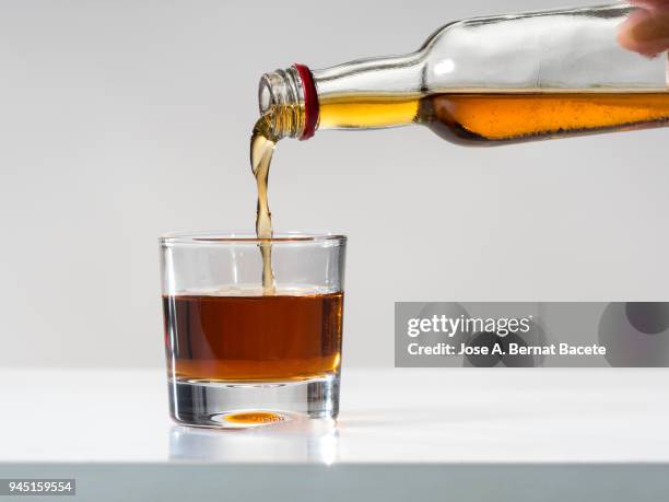 glass of crystal of chupito fill of an alcoholic drink, filling them with a bottle of drink. - smart studio shot stockfoto's en -beelden