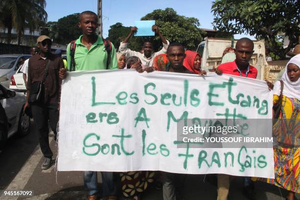 People demonstrate by the French Embassy as they hold anti-French placard reading 'The only foreigners in Mayotte are the French' in protest to the...