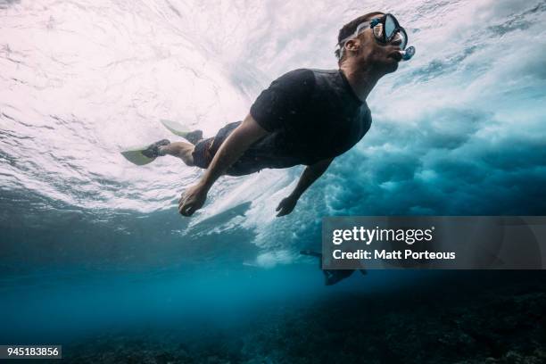 man diving below the waves - free diving stockfoto's en -beelden