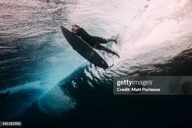 surfer dives beneath a wave - surfing stock-fotos und bilder