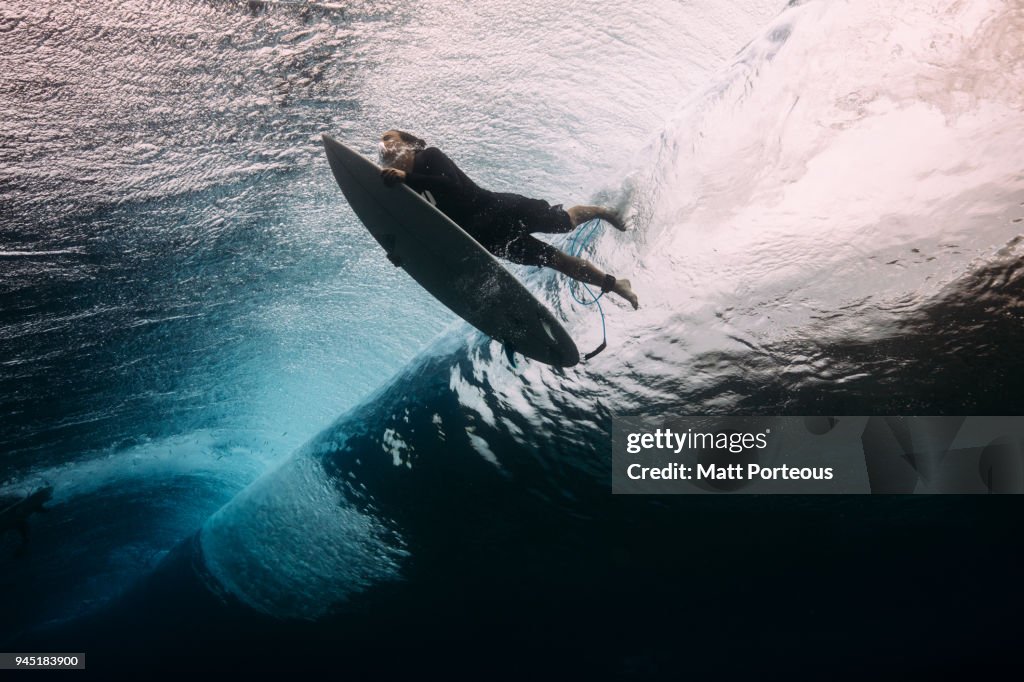 Surfer dives beneath a wave