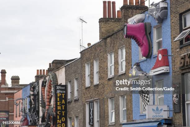 Low angle photograph showing three dimensional, decorative advertisements, such as giant shoes, including Nike, New Balance, Van's, All Star's, Dr...