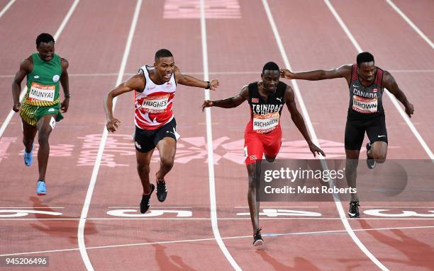 Zharnel Hughes of England crosses the line to win gold ahead of Jereem Richards of Trinidad and Tobago and Aaron Brown of Canada in the Men's 200...