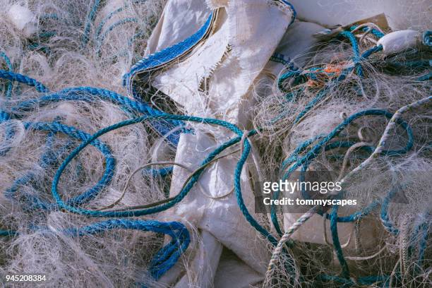 plastic fishing nets and ropes in a mess - fischereinetz stock-fotos und bilder