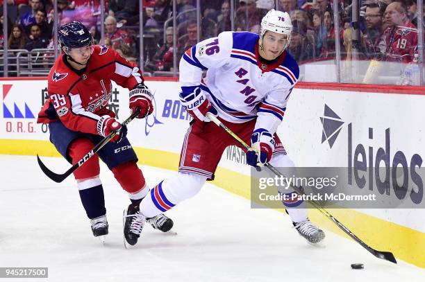 Brady Skjei of the New York Rangers controls the puck against Alex Chiasson of the Washington Capitals in the second period at Capital One Arena on...